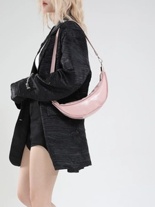Pale pink crescent moon shoulder bag in premium leather worn by model on black suit
