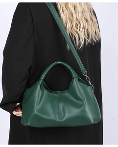 Close-up of dark green textured leather handbag with intricate rope-wrapped handle detail