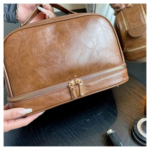 Detail of vintage brown leather makeup bag with gold zippers and pebble texture
