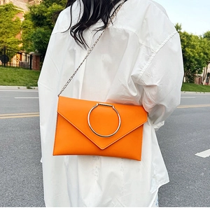 Détail de la pochette enveloppe orange vif avec grand anneau argenté et bandoulière