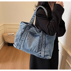 Close-up of vintage washed blue denim tote bag texture and reinforced stitching details