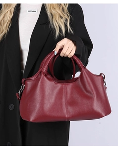 Detailed close-up of wine red litchi grain leather handbag with round handle and metal hardware