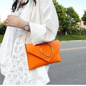 Détail de la pochette enveloppe orange vif avec grande poignée en anneau métallique