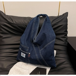 Detail of blue denim hobo bag featuring white contrast stitching and mini outer pocket