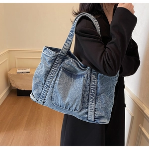 Detail of vintage washed denim tote bag showing acid wash texture and front pockets