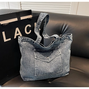 Detailed macro view of retro washed denim tote bag featuring a practical front button pocket