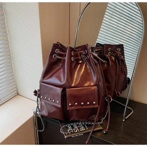 Close-up of a burgundy bucket bag with studded pockets and chain shoulder strap
