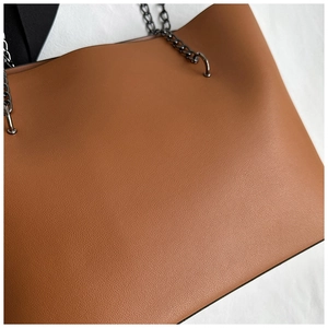 Close-up of caramel brown tote bag showing lychee grain leather and black metal chain