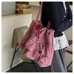 Detail view of red and white gingham canvas tote bag with ruffled design and drawstring