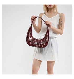 Detailansicht der dunkelroten Lackledertasche mit silbernen Nieten und glänzender Textur