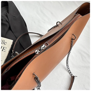 Close-up of metal zipper and large interior compartment of caramel brown tote bag
