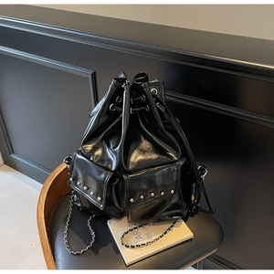 Detail of black glossy drawstring bucket bag with silver studs and chain strap