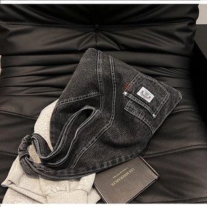 Detail of washed grey denim hobo bag featuring white contrast stitching and knotted strap