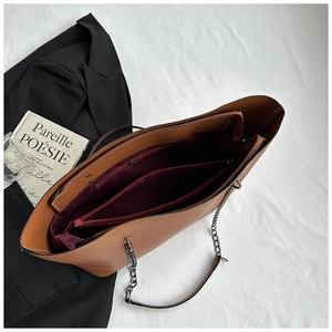 Detail view of the brown tote bag's spacious interior with red lining and compartments