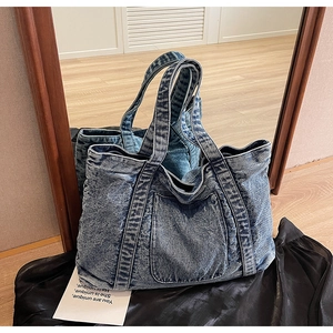 Detail of vintage blue denim tote bag with square pocket on a stylish black satin fabric
