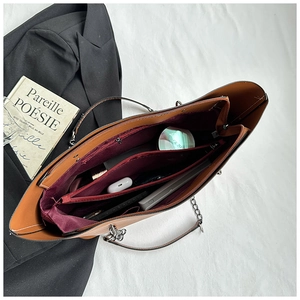 Top view of spacious brown leather tote interior showing red lining and compartments