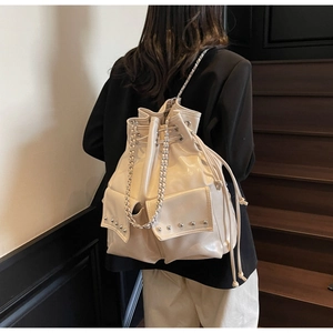 Detail of cream white bucket bag with drawstring closure and silver rivet pockets
