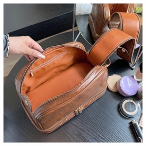 Detail of the large vintage brown leather makeup bag showing dual zipper and orange interior
