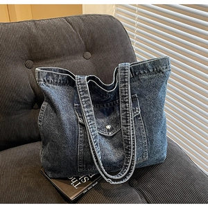 Detail of vintage denim tote bag showing washed fabric texture and front pocket on sofa
