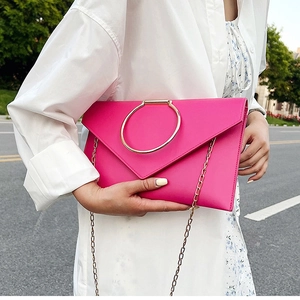 Détail de la pochette enveloppe rouge rose avec grande poignée anneau doré et chaîne métal