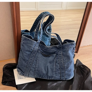 Close-up of vintage blue denim tote bag with white contrast stitching and large front pocket