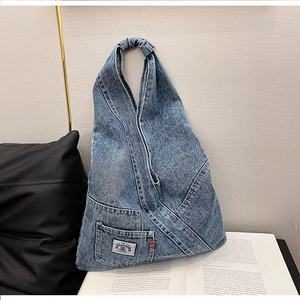 Detail of blue washed denim hobo bag featuring functional pocket and space themed patch