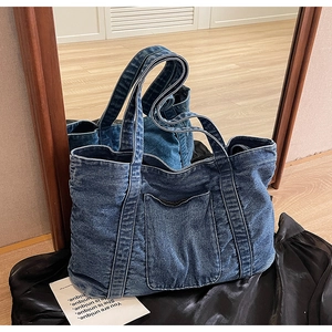 Close-up of vintage dark blue denim tote bag with a functional front pocket and stitching