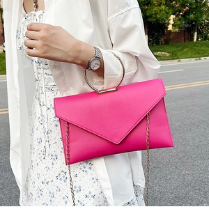 Détail de la pochette fuchsia avec poignée anneau doré et bandoulière chaîne