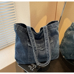 Detailed shot of dark blue denim tote bag with metal button pocket and vintage texture