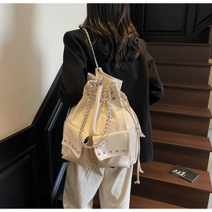 Detail of beige rivet bucket bag showing silver chain straps and large capacity with model