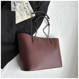 Detail of burgundy tote bag showing white stitching and metal chain handle on fabric