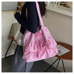 Detail view of pink plaid canvas tote bag with ruffled edges and drawstring closure