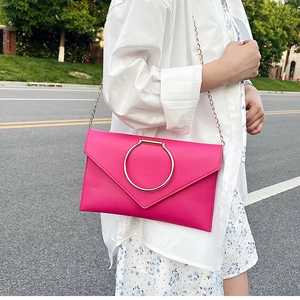 Détail de la pochette enveloppe fuchsia avec grand anneau doré et fine bandoulière chaîne
