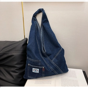Detail of blue denim hobo bag showing functional pocket with rainbow patch embroidery
