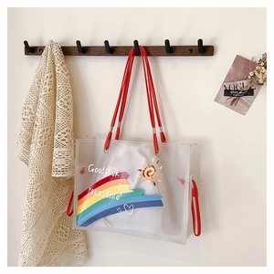 Detail of transparent PVC tote bag with rainbow prints and red shoulder straps