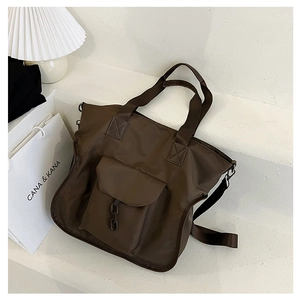Close-up of a dark brown nylon tote bag featuring a front flap pocket and black chain detail