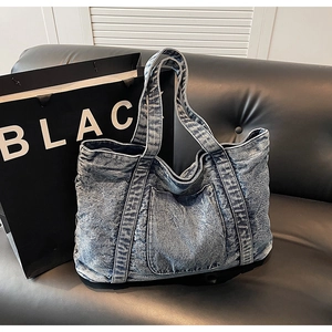 Detail of vintage washed denim tote bag showing distressed texture and front pocket design