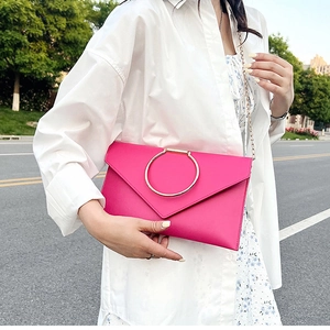 Détail de la pochette enveloppe rose avec poignée anneau doré et bandoulière en chaîne