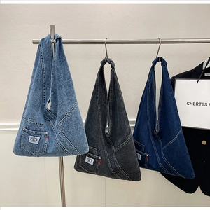 Detail of three denim tote bags in light blue, grey, and dark blue with rainbow labels