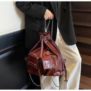 Burgundy bucket bag with silver studs and chain strap shown on a fashion model