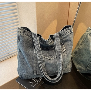 Detail of blue denim tote bag showing front pocket and washed fabric texture