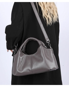 Detail view of large dark grey pebbled leather handbag with woven handle and shoulder strap