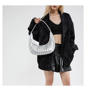Detailaufnahme der silbernen Hobo-Tasche mit Nieten, getragen von Model in schwarzer Lederkleidung