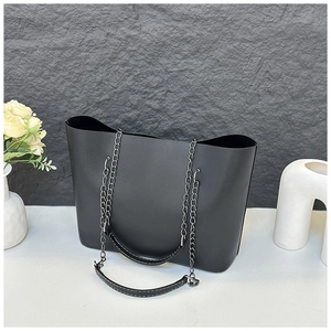 Detailed shot of black tote bag featuring metal chains and white contrast stitching