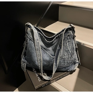 Detail shot of vintage denim tote bag on stone steps featuring metallic hardware and stitching