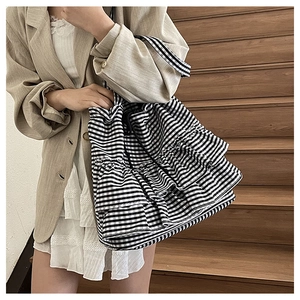Detail of checkered ruffled tote bag worn by model with layered frill design and drawstring