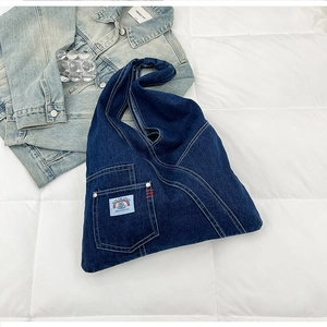 Detailed view of dark blue denim tote bag with rainbow patch and stitching details