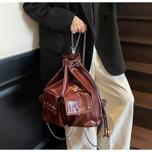 Macro detail of wine red bucket bag with drawstring closure and silver rivet accents