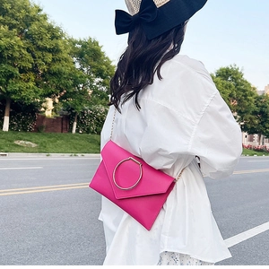 Détail de la pochette enveloppe rose avec grand anneau en métal doré et bandoulière