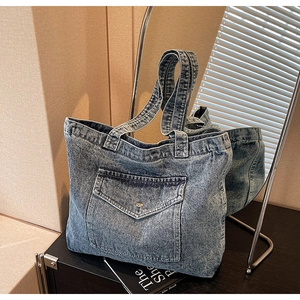 Detail of vintage blue denim tote bag with front pocket and metallic button closure